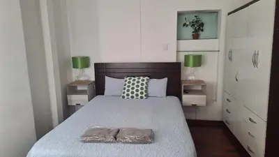 a bedroom with a bed with a wooden headboard and two lamps at Adri s House in Lima