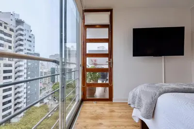 a bedroom with a bed and a balcony with a tv at ALU Apartments - Miraflores Boardwalk, Wifi 70M in Lima