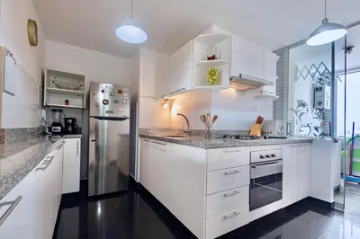 a kitchen with white cabinets and a stainless steel refrigerator at ALU Apartments - Miraflores Boardwalk, Wifi 70M in Lima