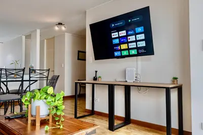 a living room with a table with a tv on the wall at ALU Apartments - Miraflores Boardwalk, Wifi 70M in Lima