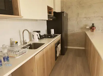 a kitchen with a sink and a black refrigerator at 2BR Apartamento Moxie Paracas con Terraza y AC en 1r Piso in Paracas