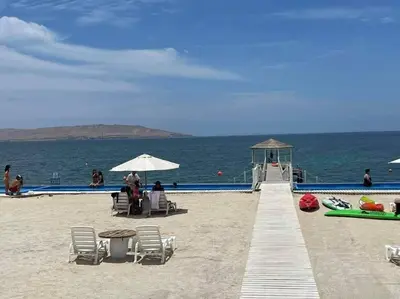 a beach with chairs and umbrellas next to the ocean at Condominio Nautico Paracas in Pisco