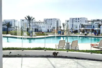 a swimming pool with chairs and buildings in the background at Condominio Nautico Paracas in Pisco