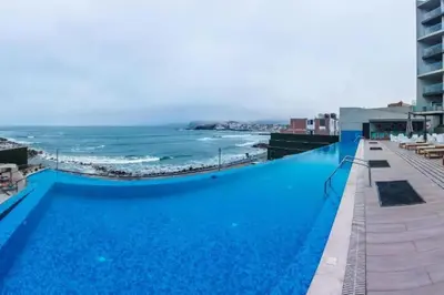 a large blue swimming pool next to the ocean at Departamento de Playa San Bartolo SOL ARENA & MAR in San Bartolo