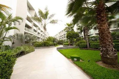 a walkway in front of a building with palm trees at Departamento de Playa San Bartolo SOL ARENA & MAR in San Bartolo
