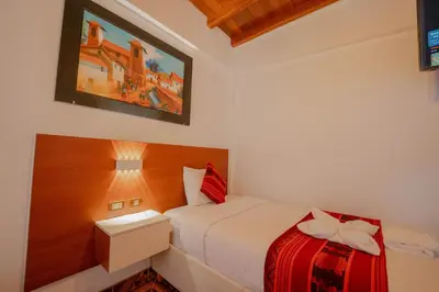 a bedroom with a bed with a red and white blanket at DANNA INN in Machu Picchu