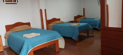 two beds with blue sheets in a room at Casa Tejedora in Chinchero