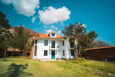 a white house with an orange roof in a yard at Hermosa casa en Valle Sagrado in Cusco