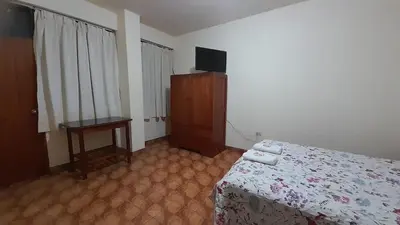 a bedroom with a bed and a tv and a table at HOSPEDAJE D`NOA En el centro de Oxapampa in Oxapampa