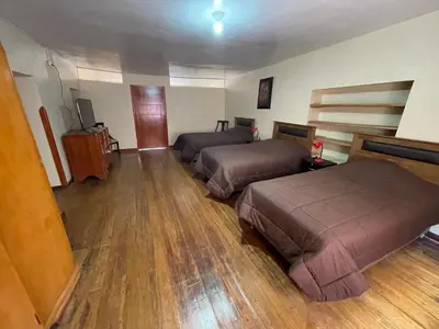 two beds in a room with wooden floors at Anka Wasi Lodging in Cusco