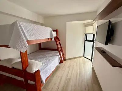 a small room with two bunk beds and a flat screen tv at Departamento amoblado in Lima