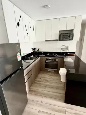 a kitchen with white cabinets and a stainless steel refrigerator at Departamento amoblado in Lima