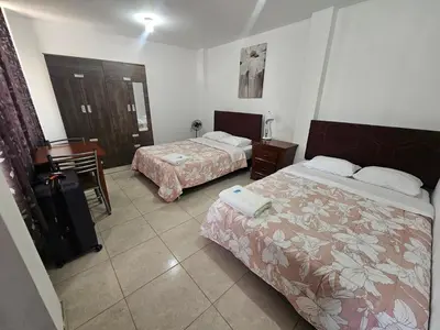 a hotel room with two beds and a table at Hospedaje Las Parraz in Ica