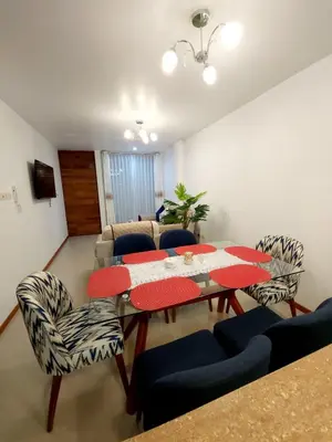 a living room with a table and chairs and a couch at Departamento familiar en Huacachina in Ica