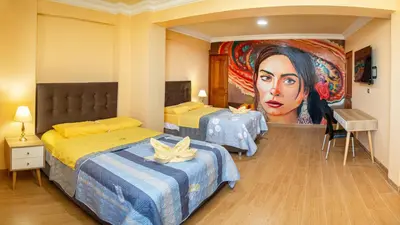 a room with two beds and a painting of a woman at Hotel Retamayo in Ica