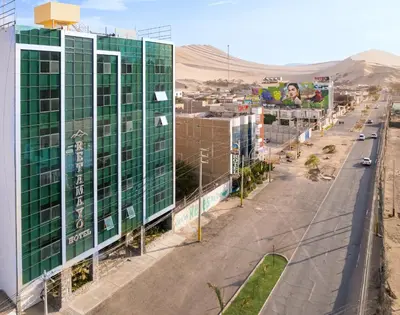a city street with a tall green building and a road at Hotel Retamayo in Ica