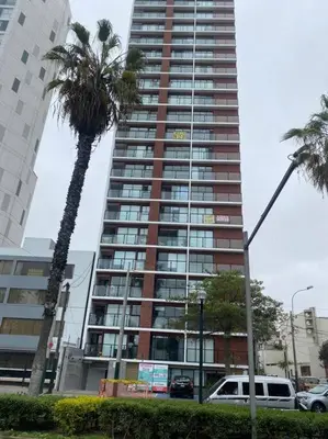 a tall building with a palm tree in front of it at Beautiful cozy Apt Barranco / Miraflores Peru in Lima