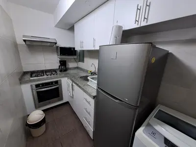 a kitchen with a stainless steel refrigerator and white cabinets at Apartamento Temporal en Miraflores in Lima