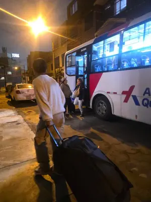 a man pulling a suitcase in front of a bus at Sabina aeropuerto hostel in Lima