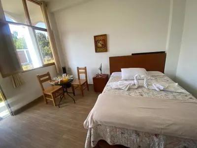 a bedroom with a bed and a table with chairs at HOTEL HACIENDA SUBTANJALLA CASABLANCA in Ica
