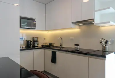 a kitchen with white cabinets and a black counter top at Caster by Wynwood House in Lima