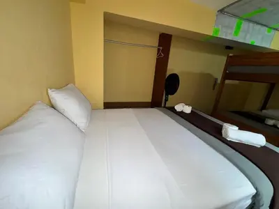 a bed with white sheets and pillows in a room at La Posada del Rey - Lima Airport Hostel in Lima