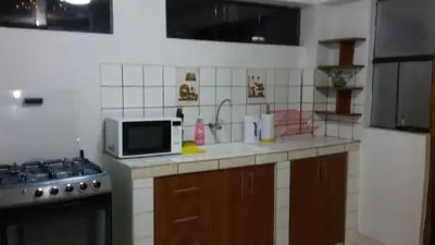 a kitchen with a stove and a microwave at Arcopata Apartamentos in Cusco