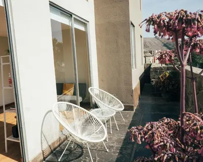 three white chairs and a tree on a balcony at Acogedor departamento con amplia terraza in Lima
