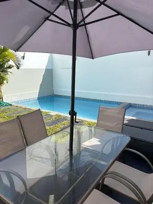 a table with an umbrella and chairs next to a pool at Killamoon House Paracas in Paracas
