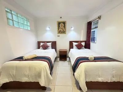 two beds in a room with two windows at Libertrek Centro Inn in Cusco