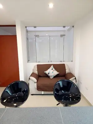 two black chairs in a living room with a couch at Acogedor departamento en Huacachina in Ica