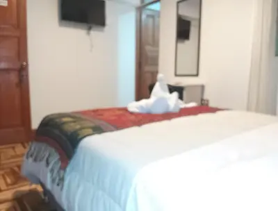 a bedroom with a bed with a white bedspread at Hostel Tupac Yupanqui House in Cusco