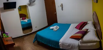 a bedroom with a bed with blue sheets and a mirror at Tupac Lima Airport in Lima