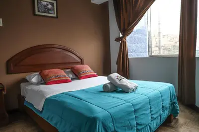 a bedroom with a bed with a blue blanket and a window at Tupac Lima Airport in Lima
