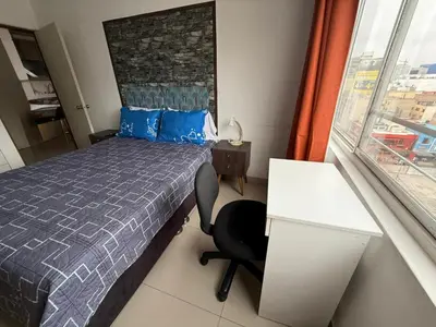 a bedroom with a bed and a desk and a window at Departamento en el corazón de Miraflores in Lima
