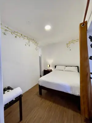 a bedroom with a white bed and a wooden floor at Casa Justina in Cusco
