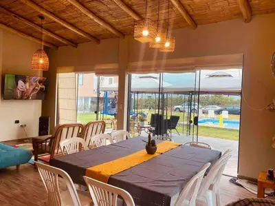 a dining room with a table and white chairs at Casa de Campo Bamboo con Piscina temperada in Lima