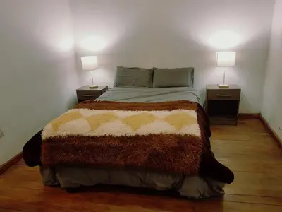 a bedroom with a bed with two lamps on two tables at Nico Homes in Cusco