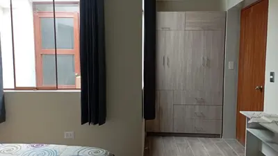 a bedroom with a bed and a closet and a window at Departamento Céntrico y Acogedor in Huancayo