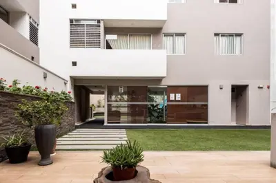 a large white house with a courtyard at Vive Cerca a Miraflores Apart. in Lima