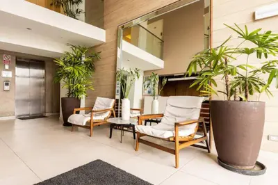 a lobby with chairs and a table and plants at Vive Cerca a Miraflores Apart. in Lima