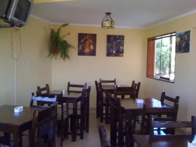 a dining room with tables and chairs and a tv at Hotel Sevilla in Ayacucho