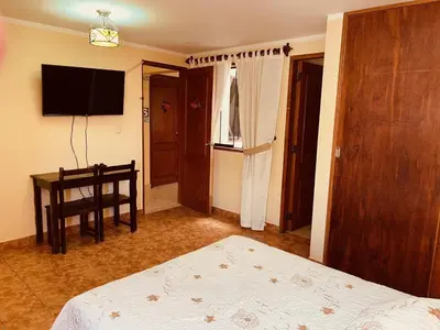 a bedroom with a bed and a table and a television at Hotel Sevilla in Ayacucho