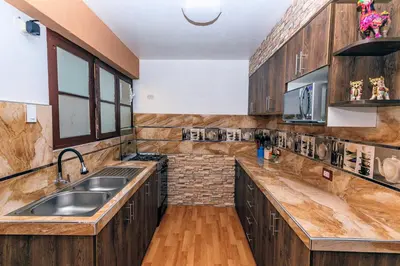 a large kitchen with wooden cabinets and a sink at PAKARINA HOUSE in Cusco