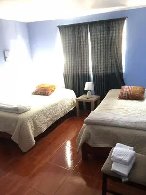 a bedroom with two beds and a blue wall at Pedraza house Airport in Lima