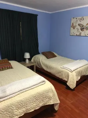 two beds in a room with blue walls at Pedraza house Airport in Lima
