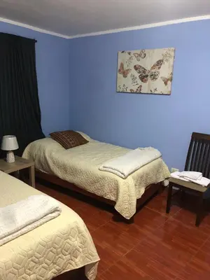 two beds in a room with blue walls at Pedraza house Airport in Lima