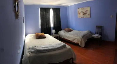 two beds in a room with blue walls at Pedraza house Airport in Lima