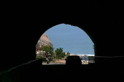 a person riding a motorcycle through a tunnel near the ocean at Agua dulce in Lima