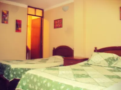 a bedroom with two beds and a door to another room at El Balcon Hostal in Ayacucho